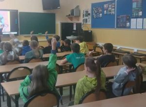 Uczniowie siedzą w ławkach i słuchają wykładu