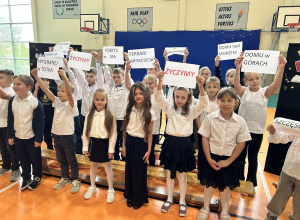 Uczniowie w strojach galowych trzymają życzenia